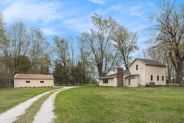 view of side of property with a chimney, a yard, and driveway