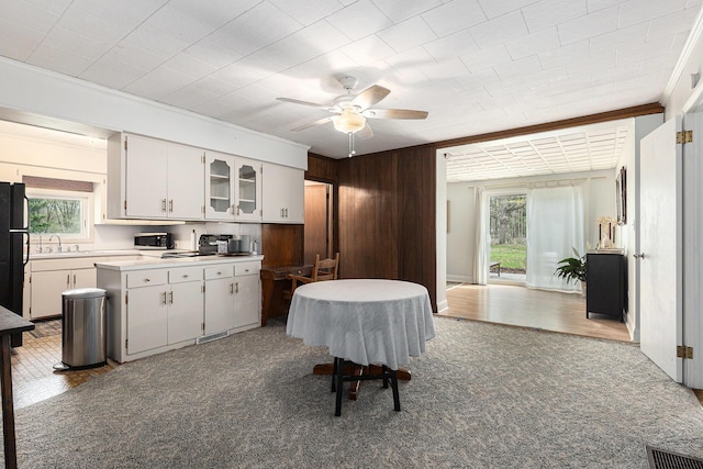 kitchen with crown molding, light countertops, a sink, white cabinets, and stainless steel microwave