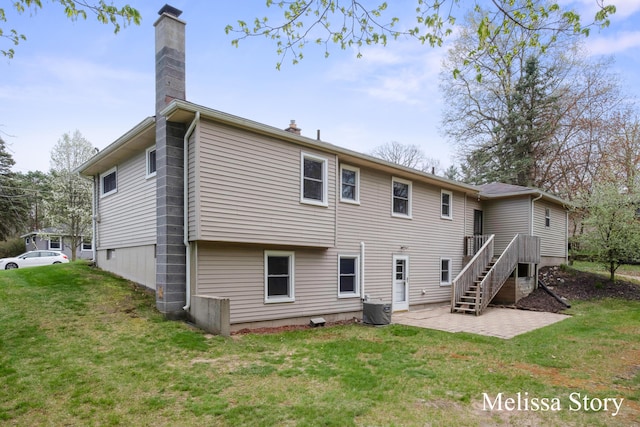 rear view of property with a lawn, a chimney, a patio area, and central AC