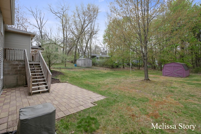 view of yard with a storage unit, a deck, stairway, an outbuilding, and a patio