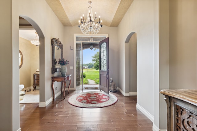 11599 Erins Way, Romeo, MI 48065 - foyer with arched walkways, a chandelier, wood finished floors, vaulted ceiling, and baseboards
