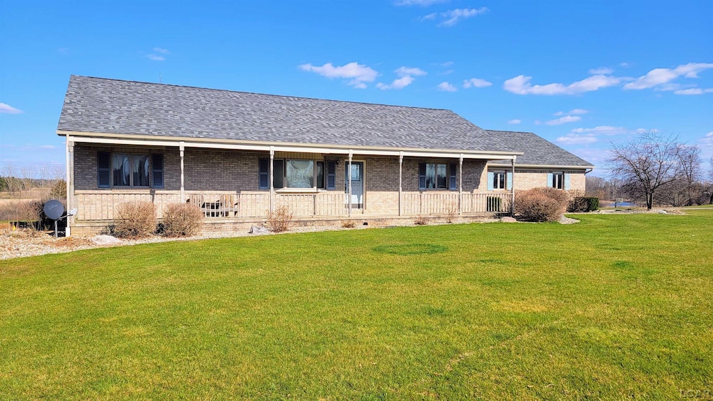 ranch-style home featuring roof with shingles, a front yard, a porch, and brick siding