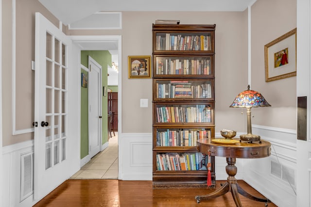 sitting room with a wainscoted wall, wood finished floors, and french doors