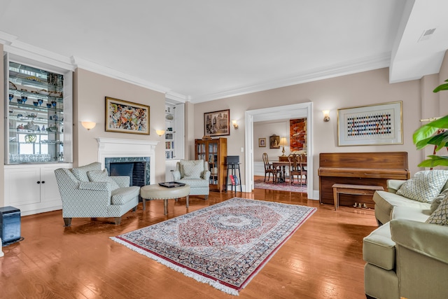 living area featuring ornamental molding, wood finished floors, and a fireplace