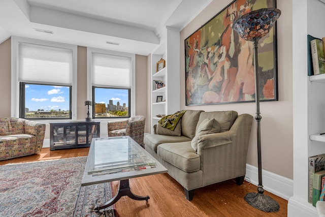 living area featuring wood finished floors, baseboards, and built in features