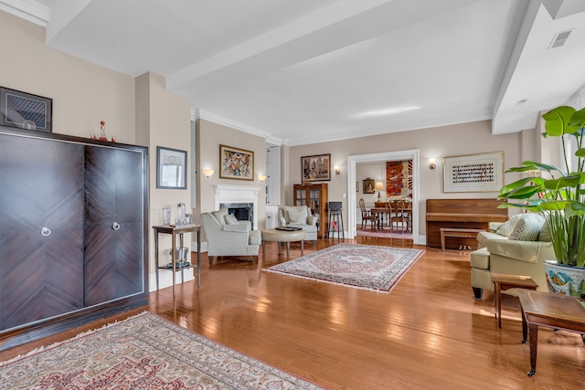 living area featuring wood finished floors, a fireplace, and ornamental molding