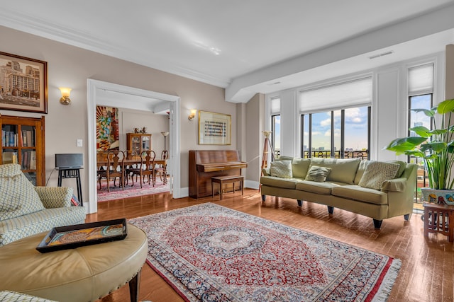 living area with wood finished floors, baseboards, and crown molding