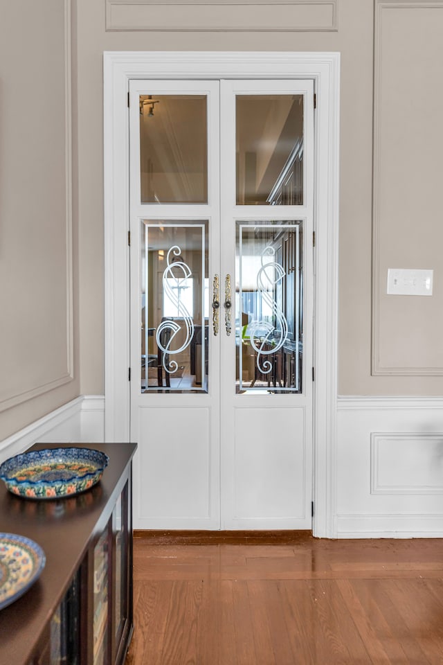 detailed view of a decorative wall, french doors, and wood finished floors