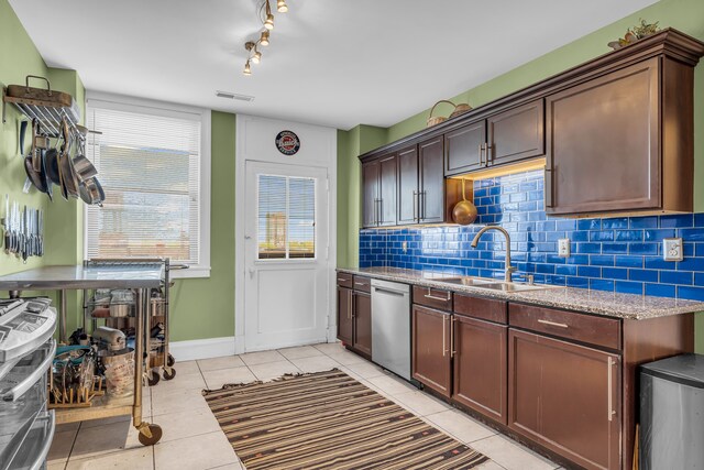 kitchen featuring dishwasher, a sink, light tile patterned flooring, and tasteful backsplash