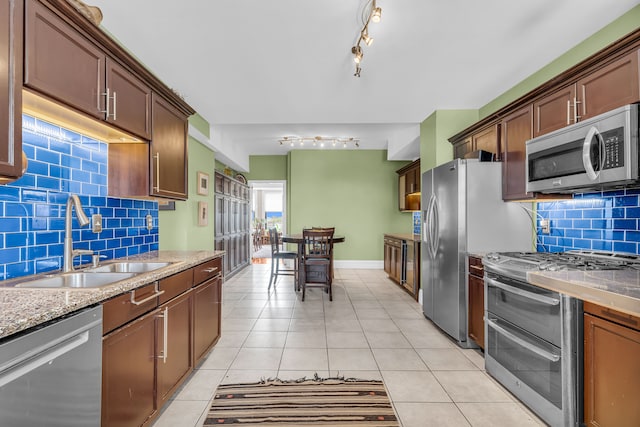 kitchen featuring stainless steel appliances, a sink, tasteful backsplash, and track lighting