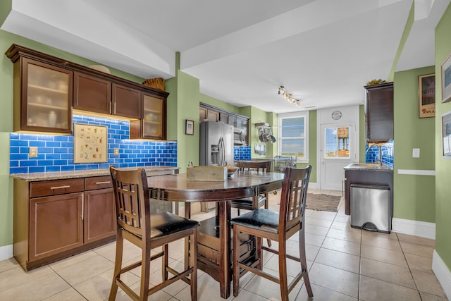 dining space with baseboards, light tile patterned floors, and rail lighting