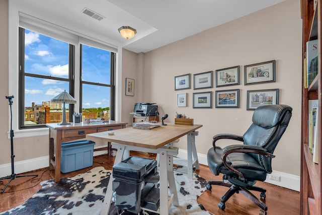 home office with plenty of natural light, baseboards, and wood finished floors