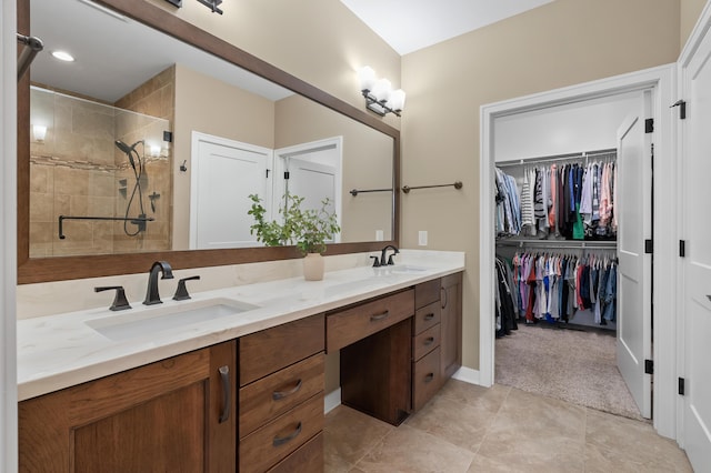 full bathroom with a sink, a shower stall, double vanity, and a spacious closet