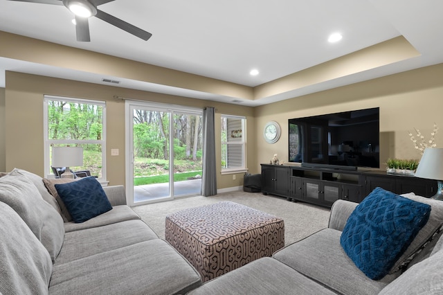 living room with light colored carpet, a ceiling fan, visible vents, and a healthy amount of sunlight