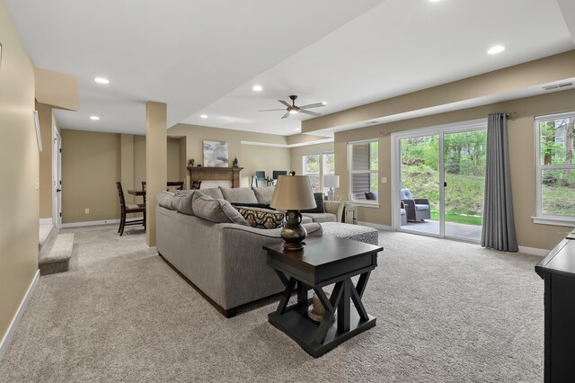 living area featuring visible vents, carpet flooring, baseboards, and a ceiling fan