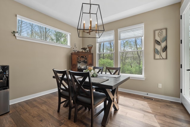 dining area with dark wood-style flooring, a chandelier, baseboards, and visible vents
