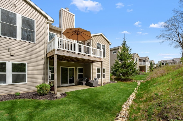back of house with a lawn, a wooden deck, a chimney, and a patio