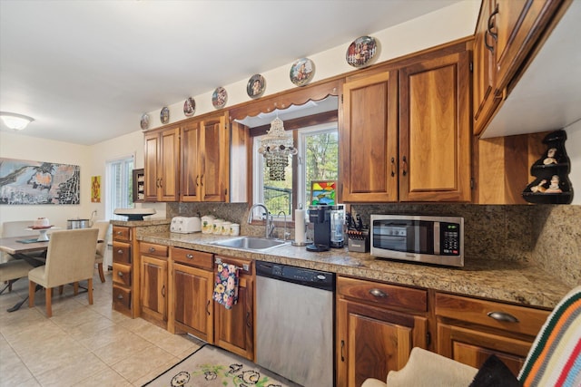 kitchen featuring a sink, appliances with stainless steel finishes, light tile patterned flooring, and tasteful backsplash