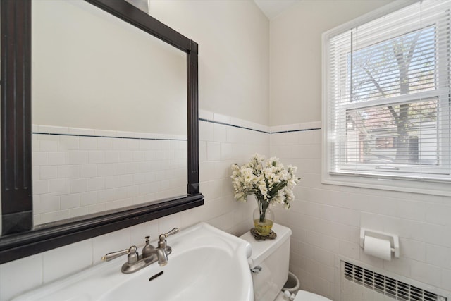 half bathroom featuring radiator heating unit, tile walls, and a wealth of natural light