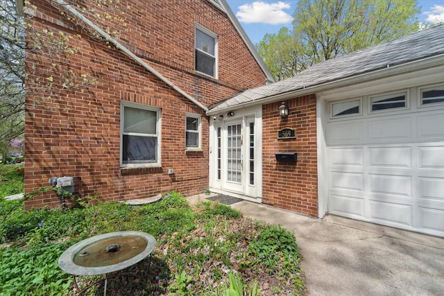 property entrance with brick siding, a shingled roof, and a garage