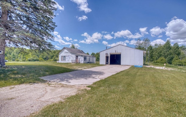 view of front of house with a garage, a front yard, a pole building, concrete driveway, and an outbuilding