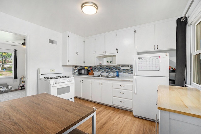 kitchen with light countertops, white cabinets, backsplash, and white appliances