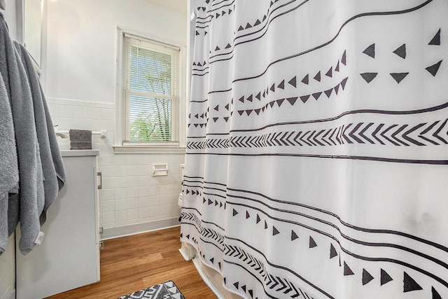 bathroom with tile walls, curtained shower, wood finished floors, a wainscoted wall, and vanity