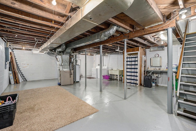 unfinished below grade area with gas water heater, independent washer and dryer, stairway, a sink, and heating unit