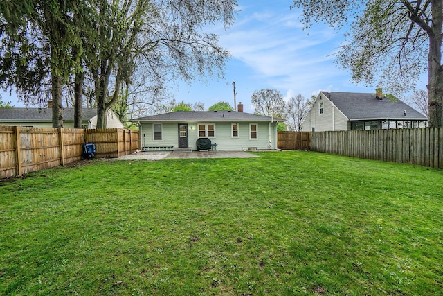 rear view of house with a lawn, a patio, a chimney, and a fenced backyard