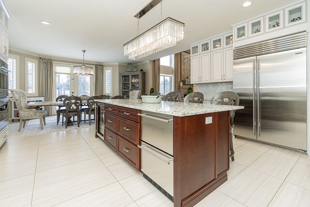 3960 Harvest Creek Ct, Rochester, MI 48306 - kitchen featuring an inviting chandelier, a kitchen breakfast bar, built in refrigerator, backsplash, and decorative light fixtures