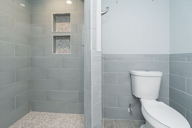 3960 Harvest Creek Ct, Rochester, MI 48306 - bathroom featuring a tile shower, toilet, tile walls, and wainscoting