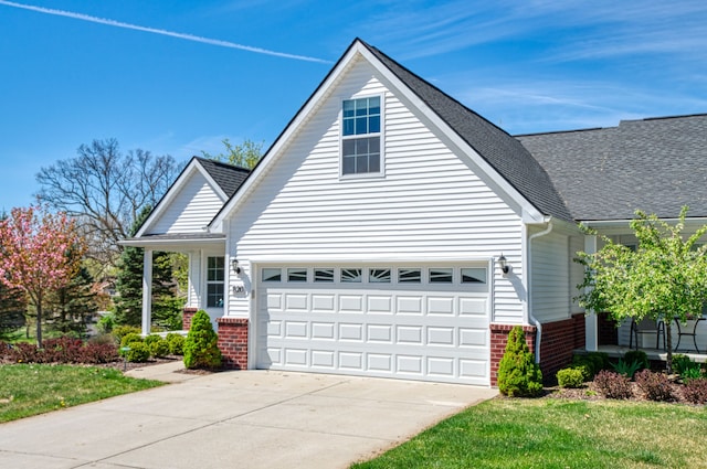 traditional home featuring brick siding, driveway, a garage, roof with shingles, and a front yard