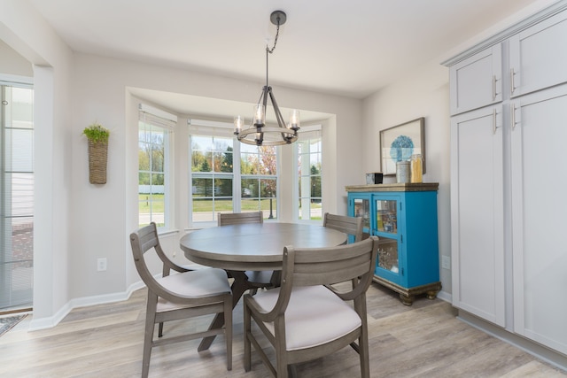 dining area with a chandelier, light wood-style flooring, and baseboards