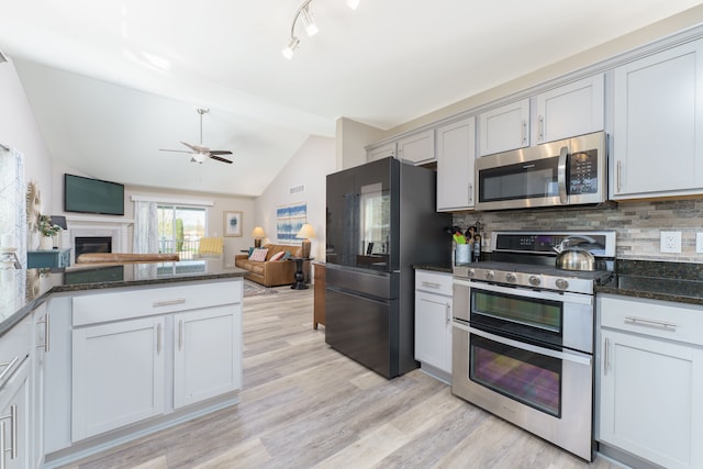 kitchen featuring stainless steel appliances, lofted ceiling, backsplash, open floor plan, and light wood-style flooring