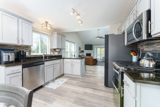 kitchen with appliances with stainless steel finishes, a sink, ceiling fan, open floor plan, and lofted ceiling