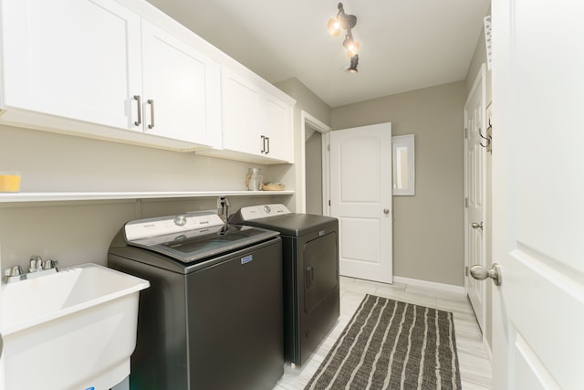 laundry room featuring washing machine and dryer, cabinet space, and baseboards