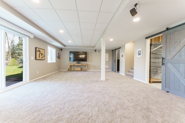 unfurnished living room featuring a barn door, carpet, baseboards, recessed lighting, and stairway