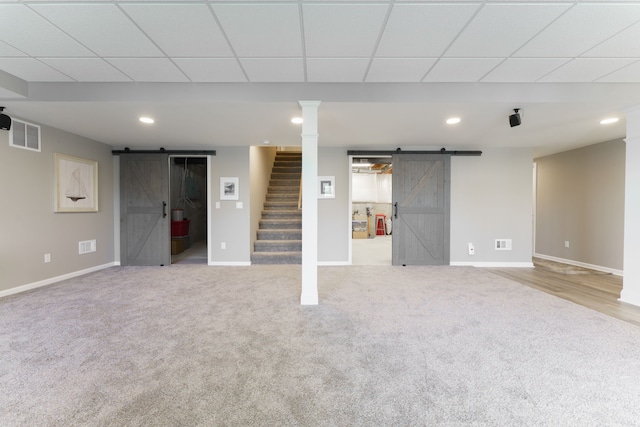 finished below grade area with a barn door, stairway, carpet floors, baseboards, and recessed lighting