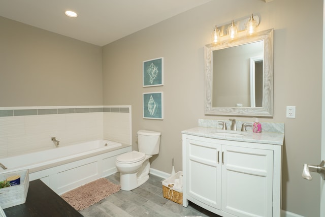 bathroom featuring toilet, wood finished floors, a bath, vanity, and baseboards