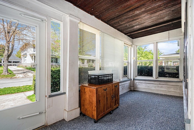 sunroom featuring a healthy amount of sunlight, wooden ceiling, and carpet flooring