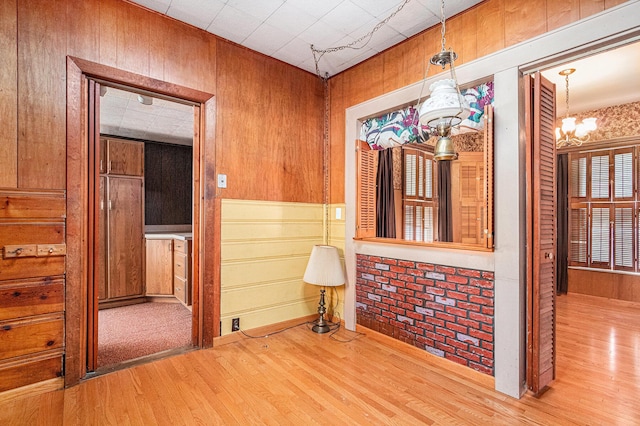 spare room with wooden walls, a notable chandelier, and wood finished floors