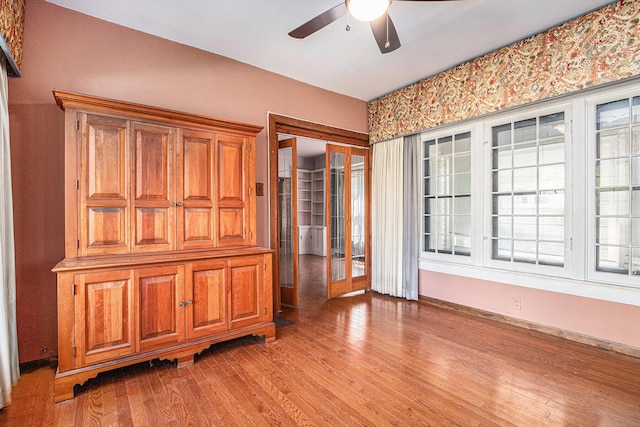 empty room with a ceiling fan, baseboards, and light wood-style floors
