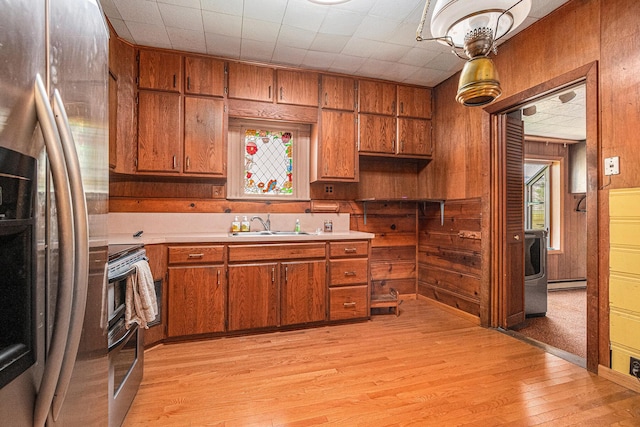 kitchen with stainless steel fridge, brown cabinetry, light wood-style floors, and baseboard heating