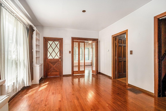interior space with baseboards, visible vents, french doors, and hardwood / wood-style floors