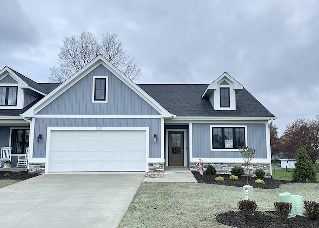 craftsman-style house featuring board and batten siding, driveway, roof with shingles, and a garage