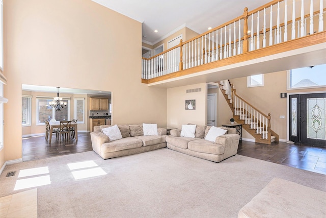 living room featuring an inviting chandelier, carpet floors, visible vents, and a towering ceiling