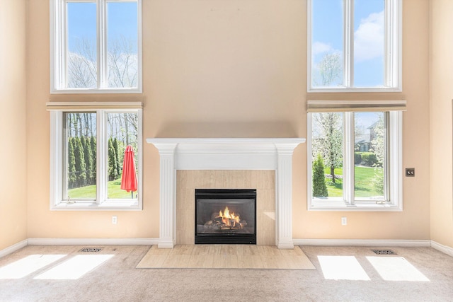 unfurnished living room featuring a high ceiling, visible vents, and a tiled fireplace