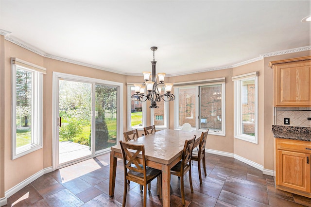 dining space featuring a healthy amount of sunlight, baseboards, and a notable chandelier