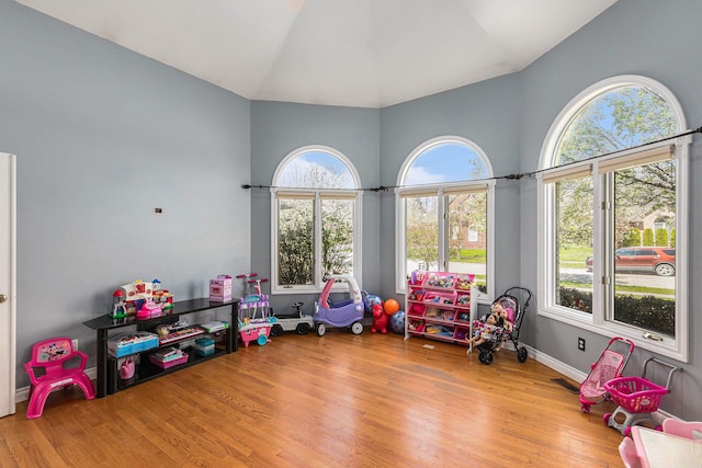 recreation room featuring a healthy amount of sunlight, high vaulted ceiling, wood finished floors, and visible vents