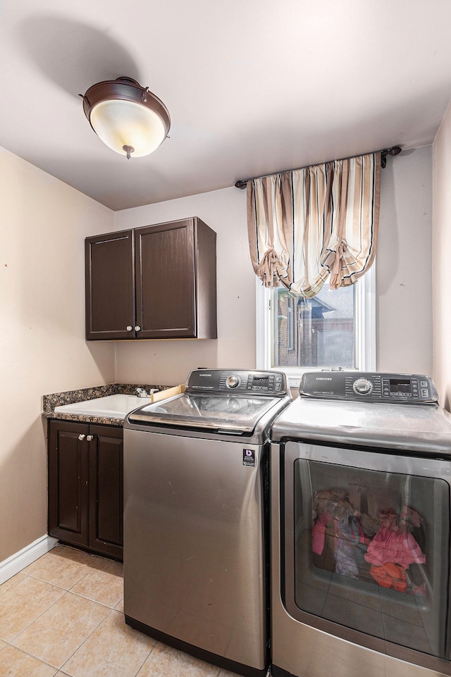 washroom with light tile patterned flooring, baseboards, a sink, cabinet space, and independent washer and dryer